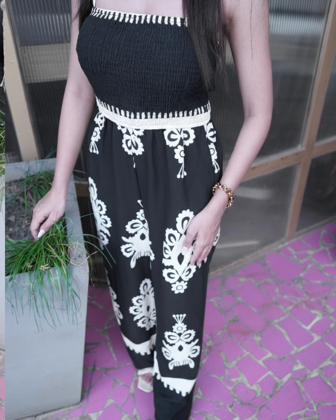 Person wearing a black outfit with white patterns on a pink floor.