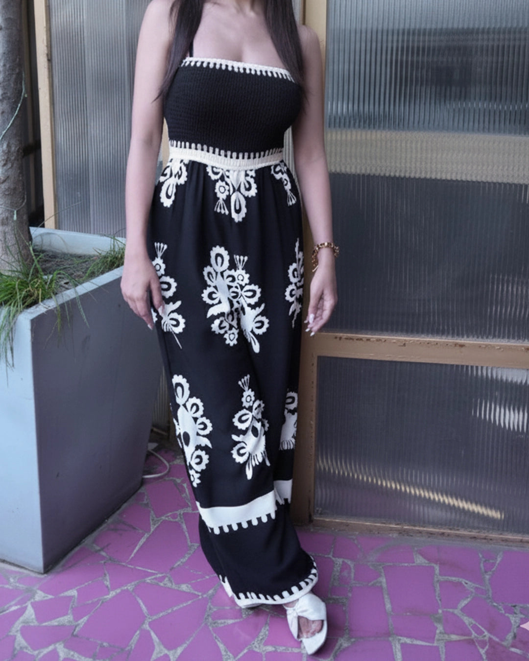 Person wearing a black and white patterned outfit standing against a glass wall.
