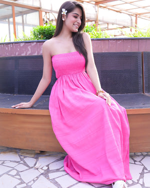 Woman in a pink dress sitting on a bench outdoors