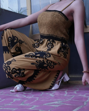Person wearing a mustard yellow outfit with black patterns on a pink floor.