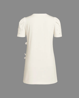 White dress with short sleeves and decorative elements on a gray background