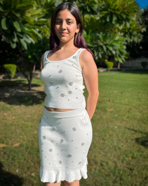 Woman wearing a white outfit with floral patterns in an outdoor setting