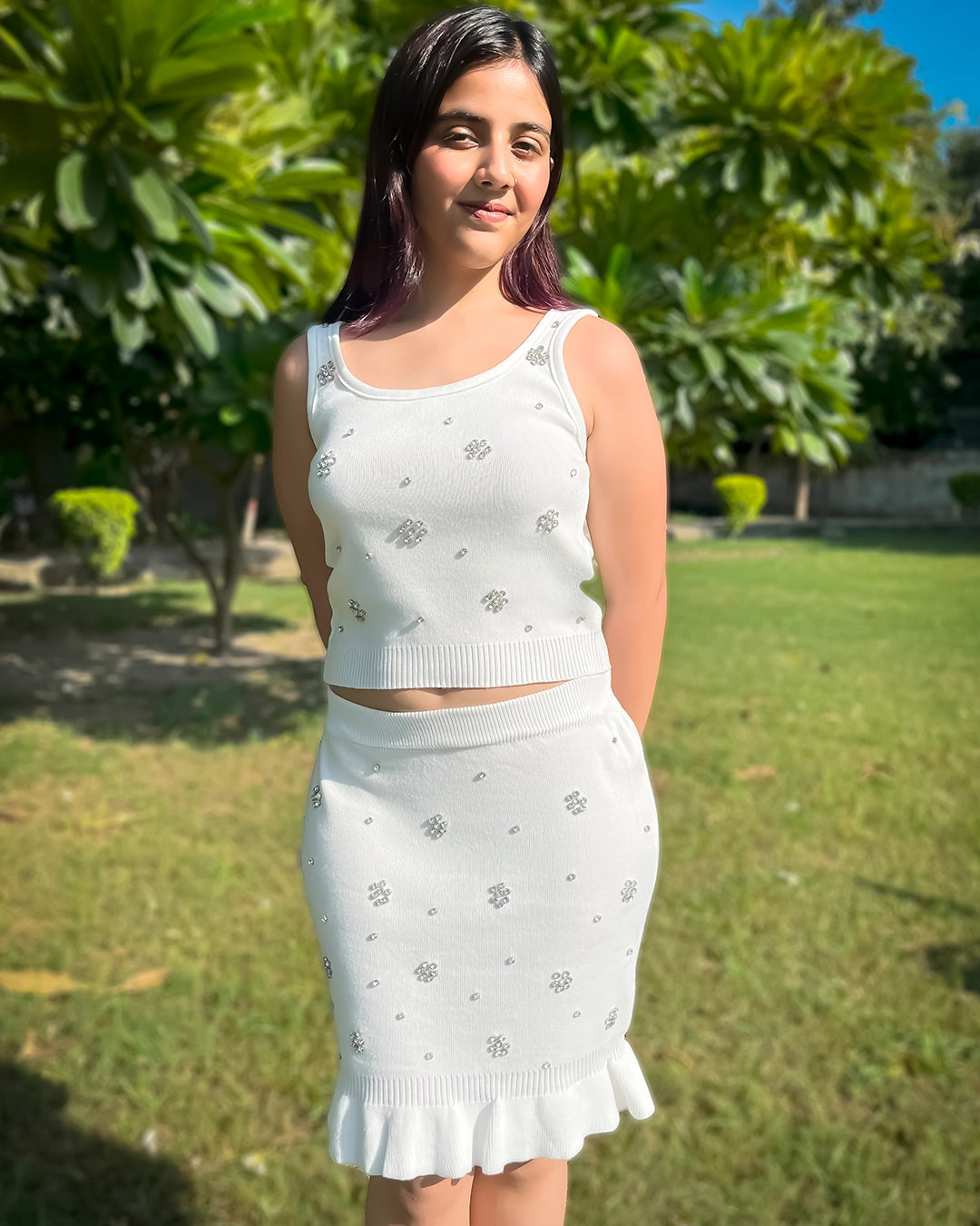 Woman wearing a white outfit with a pattern in an outdoor setting
