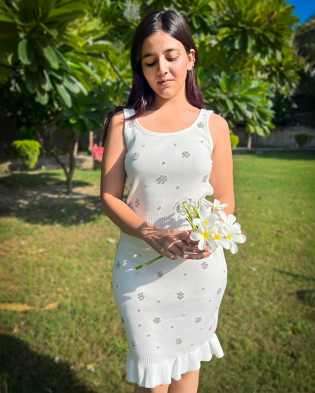 Woman in a white dress holding flowers in a garden