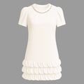 White dress with ruffled skirt and pearl neckline on a gray background