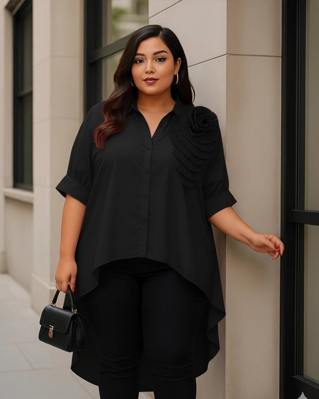 Woman wearing a black outfit with a unique sleeve design, standing against a building.