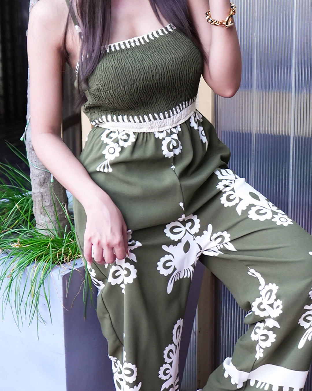 Person wearing a green dress with white lace details sitting outdoors.